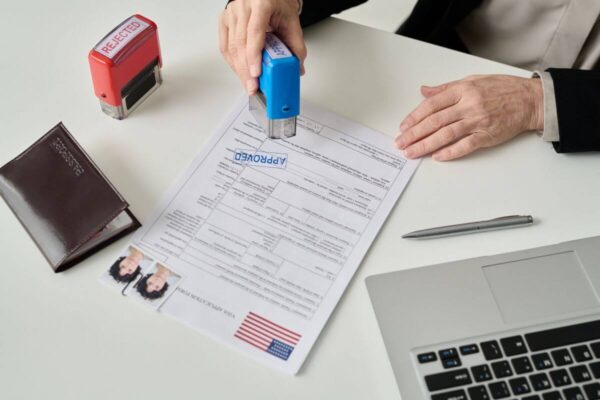 Pracownik stempluje dokument "Approved", związany z legalizacją pobytu cudzoziemców.