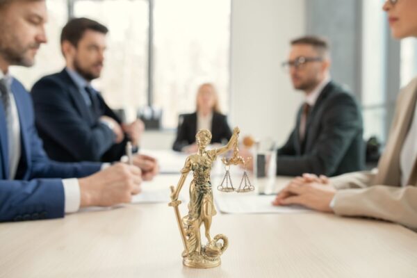 Spotkanie prawników omawiających prawo spadkowe; na pierwszym planie figurka Temidy.