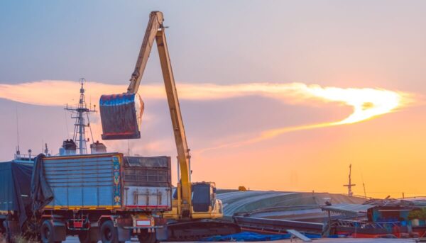 Żuraw przeładunkowy pracuje o zachodzie słońca, co ilustruje prawo transportowe w praktyce.