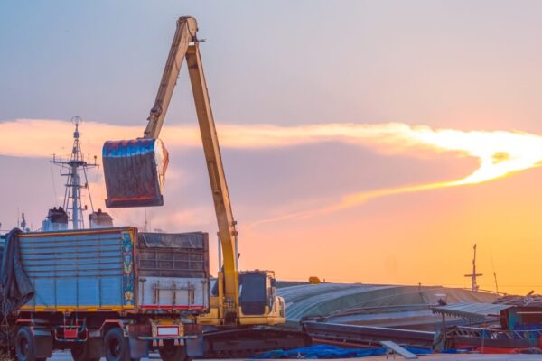Żuraw przeładunkowy pracuje o zachodzie słońca, co ilustruje prawo transportowe w praktyce.