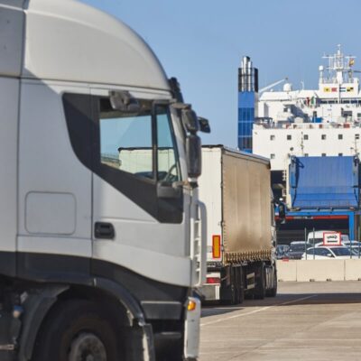 Ciężarówki czekają na załadunek na prom, co ilustruje zastosowanie prawo transportowe w praktyce.