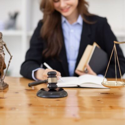 Adwokat notuje coś w biurze, obok młotek sędziowski i waga.