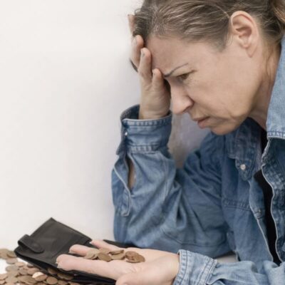 Kobieta w dżinsowej kurtce skupiona na monetach, rozważająca upadłość konsumencką.